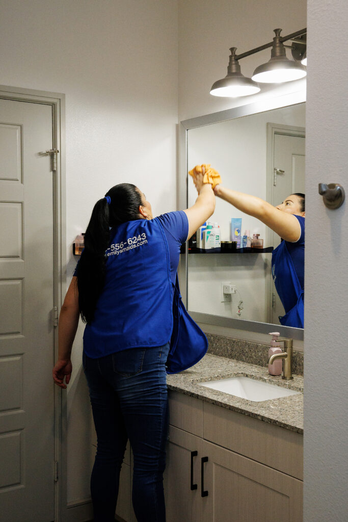 House cleaner wiping mirror
